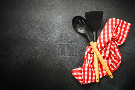 Foto de Kitchen utensil and red tablecloth on black background. Top view with copy space. - Imagen libre de derechos