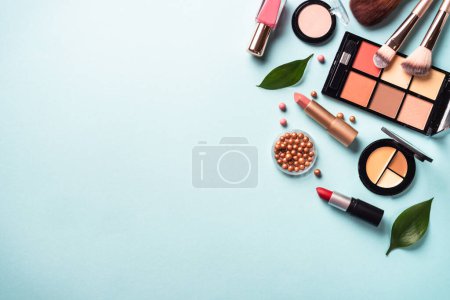 Téléchargez les photos : Cosmetic products on blue background. Cream, powder, shadow, brushes with green leaves. Flat lay image with copy space. - en image libre de droit