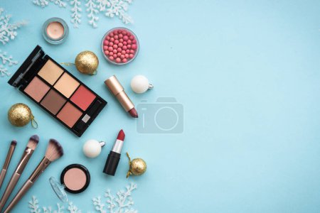 Téléchargez les photos : Make up products and winter decorations on blue background. Winter cosmetic. Flat lay image with copy space. - en image libre de droit