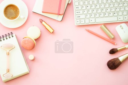 Foto de Home office workspace. Creative Pink flat lay background with keyboard, notebook, coffee cup and cosmetics.. - Imagen libre de derechos