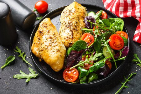 Téléchargez les photos : Salade fraîche avec filet de poulet et légumes sur assiette noire. - en image libre de droit