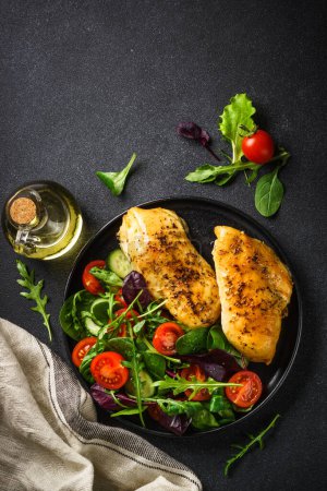 Photo for Fresh salad with chicken fillet and vegetables on black kitchen table. Healthy food, keto diet, low carb. Top view with copy space. - Royalty Free Image