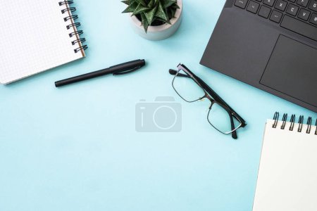 Foto de Office desk flat lay background with laptop, notepad, green plant and pen. - Imagen libre de derechos