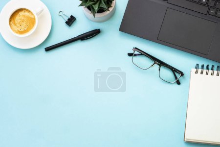 Foto de Espacio de trabajo de oficina con laptop, auriculares, bloc de notas y taza de café. Plana imagen de la puesta en azul con espacio de copia. - Imagen libre de derechos