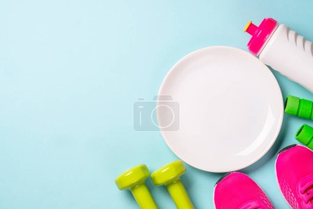 Photo for Dumbbells, white plate and sport shoes on blue. Healthy lifestile, fitness, diet and weight loss concept. - Royalty Free Image