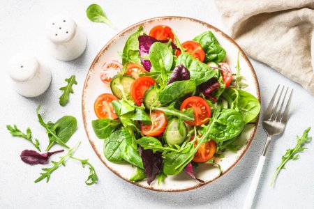 Téléchargez les photos : Green salad with fresh leaves and vegetables in white plate. Top view. - en image libre de droit