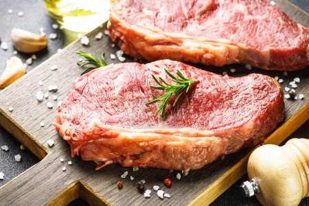 Foto de Beef steak with spices. Raw beef meat at cutting board. Close up. - Imagen libre de derechos