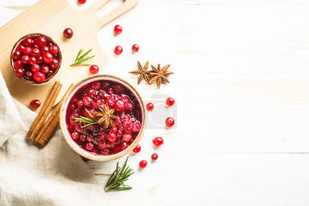 Téléchargez les photos : Cranberry sauce in a bowl with rosemary and spices. Top view at black background. - en image libre de droit