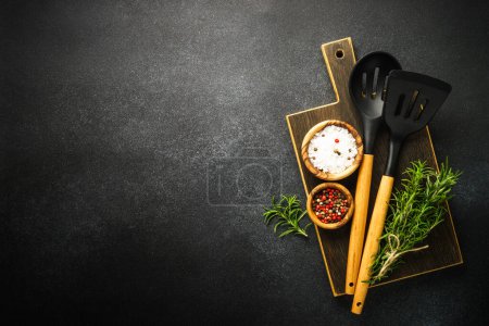 Foto de Food background. Kitchen utensils, wooden cutting board and food ingredients on black. Top view with copy space. - Imagen libre de derechos