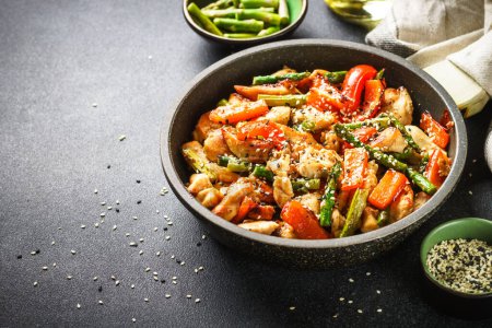 Foto de Chicken stir fry with vegetables and sesame in the skillet. Close up with copy space. - Imagen libre de derechos