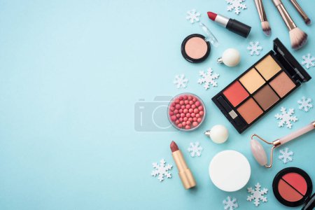 Foto de Maquillaje de productos y decoraciones de Navidad sobre fondo azul. Compras de vacaciones. Imagen plana con espacio de copia. - Imagen libre de derechos