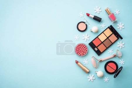 Téléchargez les photos : Winter cosmetic. Make up products and christmas decorations on blue background. Flat lay image with copy space. - en image libre de droit
