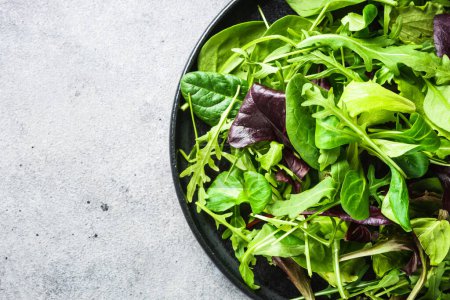 Photo for Green salad with fresh leaves assortment in black plate. Top view, close up. - Royalty Free Image