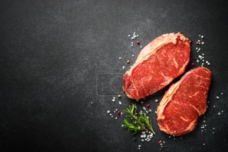 Foto de Beef steak. Raw beef meat at black. Top view with copy space. - Imagen libre de derechos