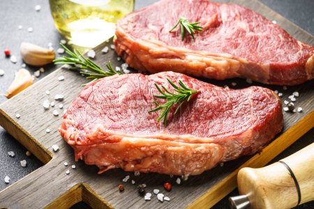 Téléchargez les photos : Steak de boeuf aux épices. Viande de bœuf crue à la planche à découper. Gros plan. - en image libre de droit