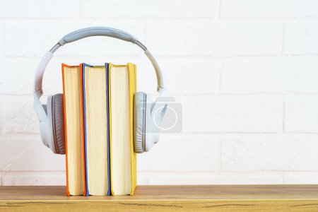 Téléchargez les photos : Audio books concept. Wireless Headphones and color books at table. - en image libre de droit