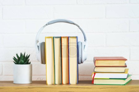 Audio books concept. Wireless Headphones and color books at table white background.