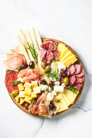 Téléchargez les photos : Assiette antipasto. Fromage et viande - jamon, salami, olives à la planche de bois à la table de marbre. Vue du dessus. - en image libre de droit