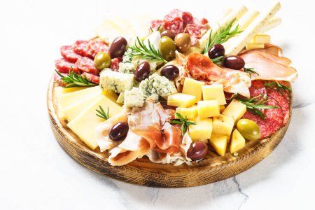 Photo for Antipasto platter. Cheese and meat - jamon, salami, olives at wooden serving board. - Royalty Free Image
