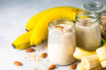 Foto de Almond banana smoothie with oat flakes in glass. Close up image. - Imagen libre de derechos