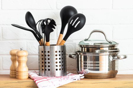 Foto de Cocina moderna con mesa de madera, utensilios de cocina, ollas de cocina y otros, fondo blanco. - Imagen libre de derechos