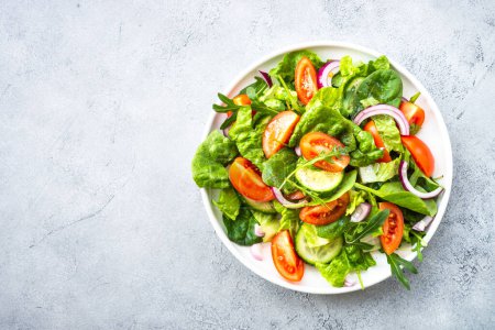 Téléchargez les photos : Salade verte fraîche aux feuilles et légumes. Vue du dessus à la table en pierre. - en image libre de droit