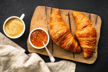 Foto de Croissant con mermelada de naranja y taza de café en la mesa de piedra vista superior. Postre tradicional o desayuno. - Imagen libre de derechos
