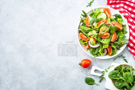Téléchargez les photos : Salade verte fraîche avec des feuilles et des légumes à fond clair. Vue supérieure avec espace de copie. - en image libre de droit