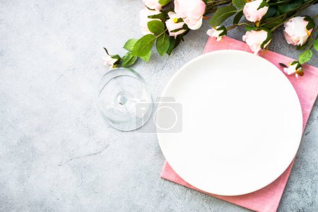 Foto de Fijación de mesa festiva con plato blanco y flores de rosa. Decoración de la mesa para un aniversario o boda. Piso con espacio de copia. - Imagen libre de derechos