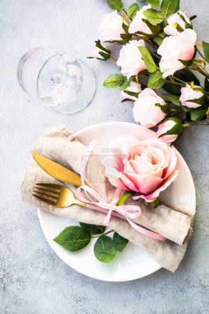 Téléchargez les photos : Table festive avec assiette blanche et fleurs roses. Décor de table pour un anniversaire ou un mariage. Pose plate avec espace de copie. - en image libre de droit