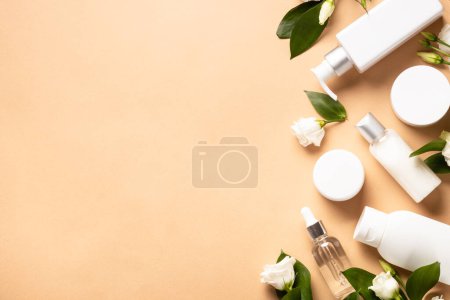 Foto de Natural cosmetic products. Cream, serum, tonic with green leaves and flowers. Flat lay image with copy space. - Imagen libre de derechos