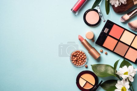 Foto de Make up products on blue background. Cream, powder, shadow, brushes. Flat lay image with copy space. - Imagen libre de derechos
