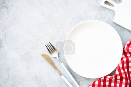Téléchargez les photos : Assiette blanche et couverts dorés à table en pierre. Réglage de la table, servir, Image de pose plate. - en image libre de droit
