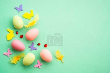 Téléchargez les photos : Fond de Pâques. Œufs, lapin, fleurs de printemps et papillon. Flat lay mock up à fond vert. - en image libre de droit