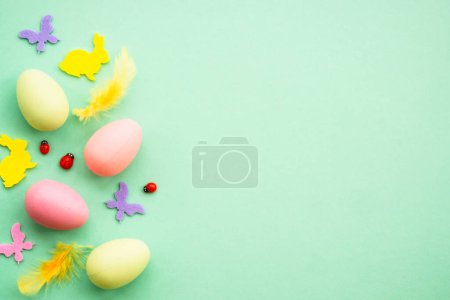 Photo for Happy Easter background. Eggs, rabbit, spring flowers and butterfly. Flat lay image at green background. - Royalty Free Image