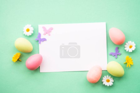 Foto de Tarjeta de felicitación de Pascua con huevos, flores y mariposas en el fondo de color. Imagen plana con espacio de copia. - Imagen libre de derechos
