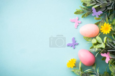 Téléchargez les photos : Fond de Pâques ou carte de vœux sur bleu. Œufs, feuilles de printemps, fleurs et papillons colorés. Pose plate avec espace de copie. - en image libre de droit