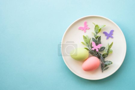 Photo for Easter table setting, White plate with eggs and green branch. Top view with copy space. - Royalty Free Image