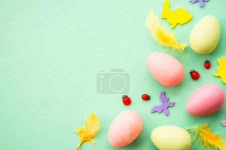 Téléchargez les photos : Fond de Pâques. Œufs, lapin, fleurs de printemps et papillon. Flat lay mock up à fond vert. - en image libre de droit
