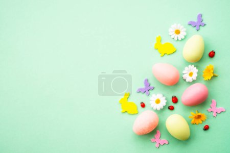 Photo for Easter background. Eggs, rabbit, spring flowers and butterfly. Flat lay mock up at green background. - Royalty Free Image