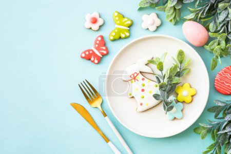 Téléchargez les photos : Fond alimentaire de Pâques. Assiette blanche avec œufs, fleurs de printemps et biscuits de Pâques. Pose plate. - en image libre de droit