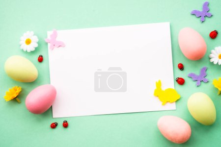 Foto de Tarjeta de felicitación de Pascua con huevos, flores y mariposas en el fondo de color. Imagen plana con espacio de copia. - Imagen libre de derechos