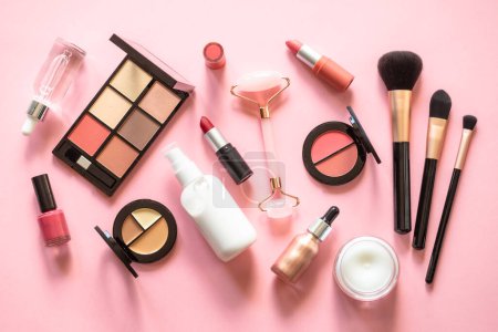 Téléchargez les photos : Makeup cosmetic products on pink background. Cream, lipstick, shadow and brushes. Flat lay image with copy space. - en image libre de droit