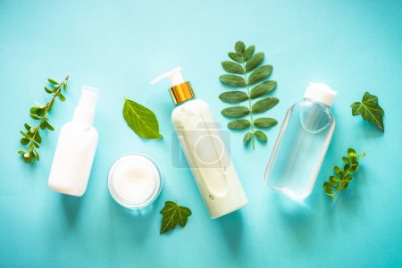 Photo for Natural cosmetics concept. Skin care product, cream, serum, soap, mask with green leaves. Flat lay image on blue with space for your text. - Royalty Free Image