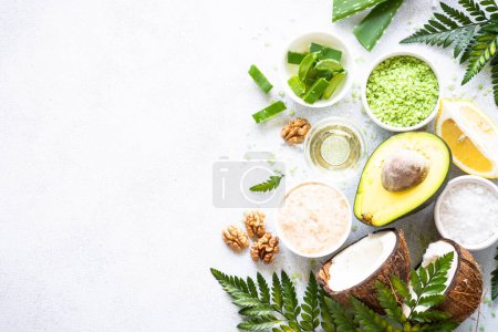 Photo for Natural cosmetic concept, homemade cosmetic laboratory. Aloe, sea salt, avocado, coconut, cosmetic oil and green leaves. Natural ingredients for healthy skin. Top view on white with copy space. - Royalty Free Image