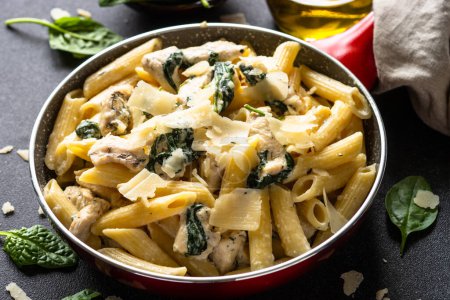 Téléchargez les photos : Pasta penne with chicken and spinach in creamy sauce in the skillet. - en image libre de droit