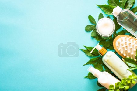 Foto de Natural cosmetics on blue. Skin care product, cream, tonic, soap, mask with green leaves. Flat lay image with copy space. - Imagen libre de derechos
