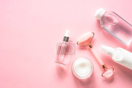 Photo for Skin care concept. Jade roller, cream and serum bottle on pink. Flat lay image with copy space. - Royalty Free Image