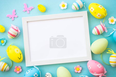 Photo for Easter greeting card on blue. Colored easter eggs with decorations and white frame for text. Flat lay with copy space. - Royalty Free Image