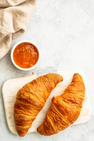Photo for Croissant with jam on cutting board at stone table top view. Traditional snack or breakfast. - Royalty Free Image